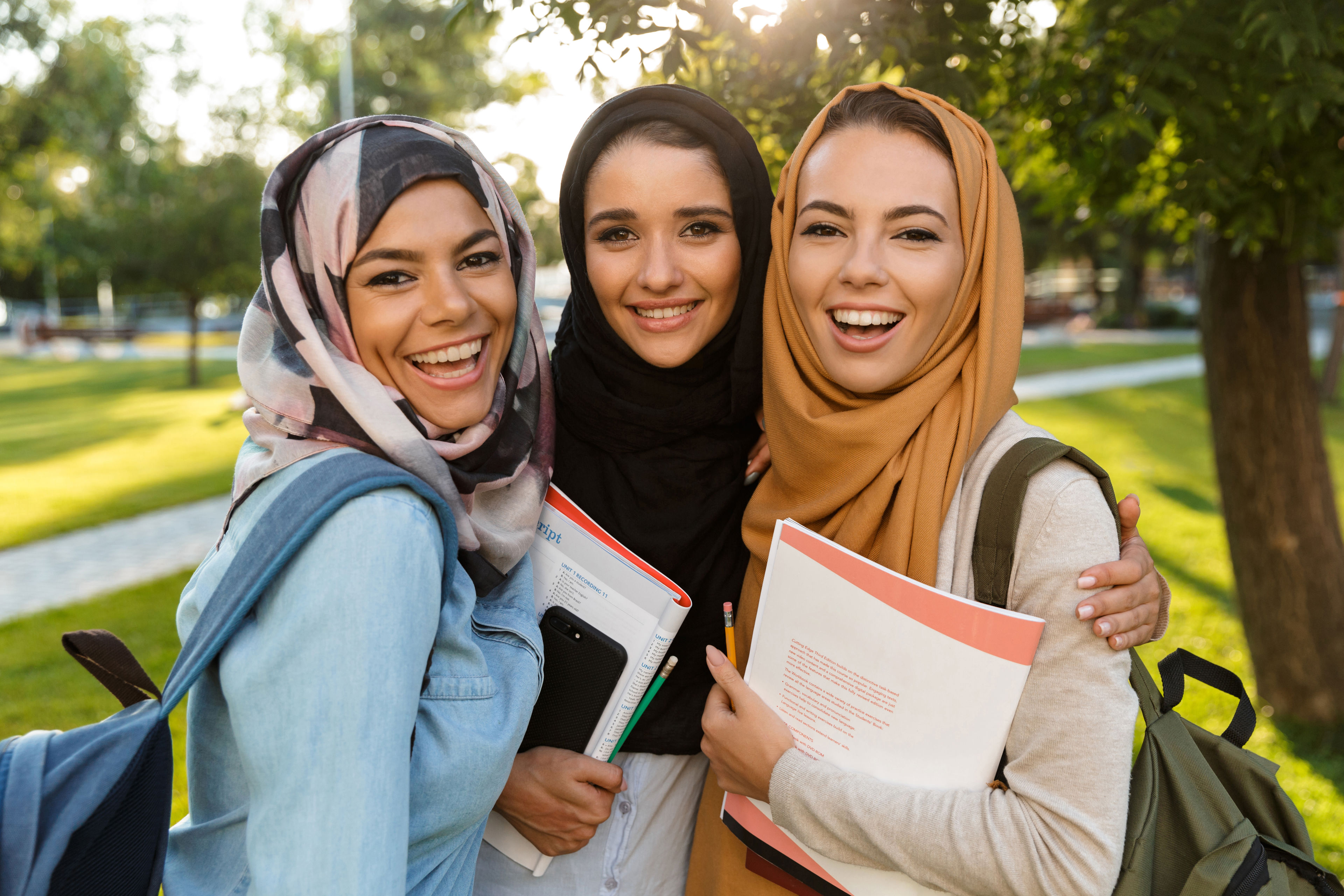 Tre kvinder iført hijab udenfor i sollys